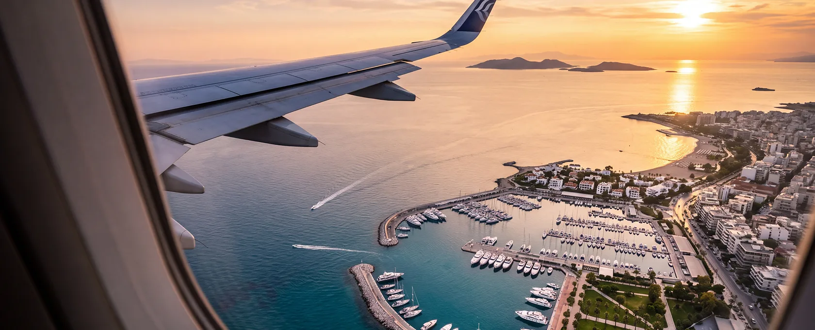 View from a plane window over a Greek coastal town at sunset
